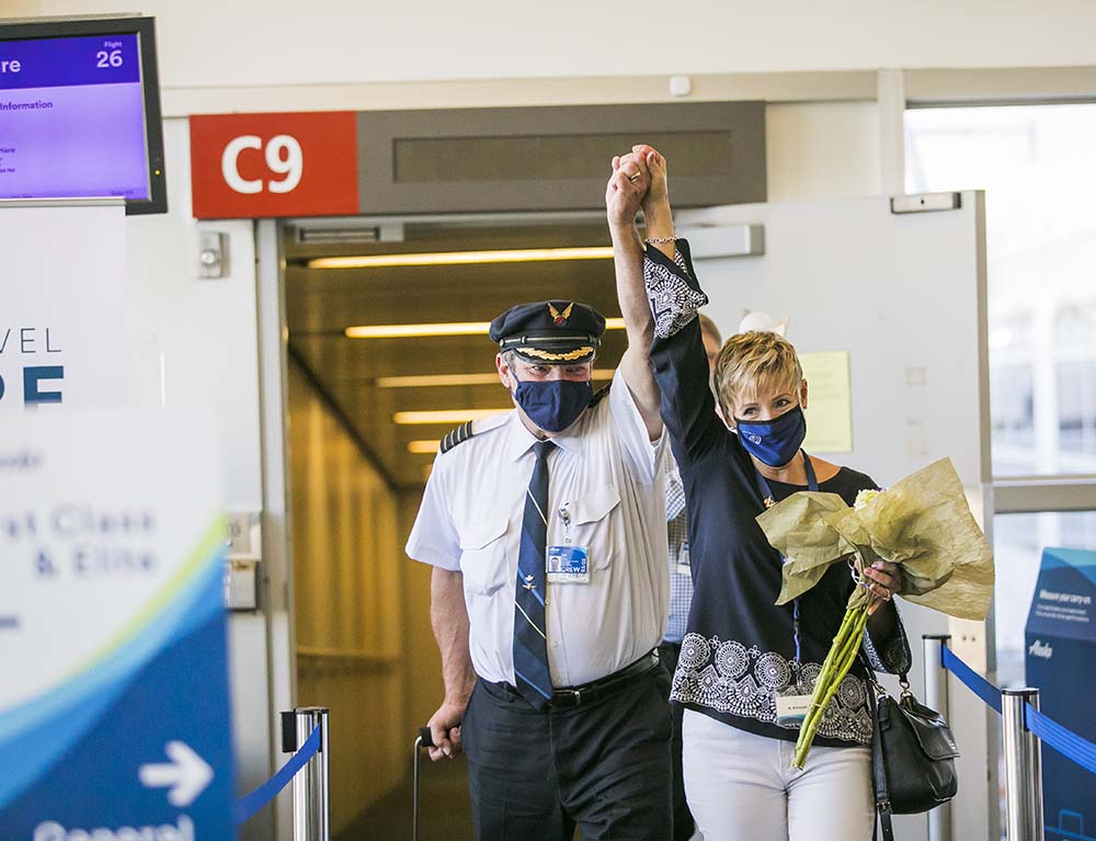 a man and woman wearing face masks and holding flowers