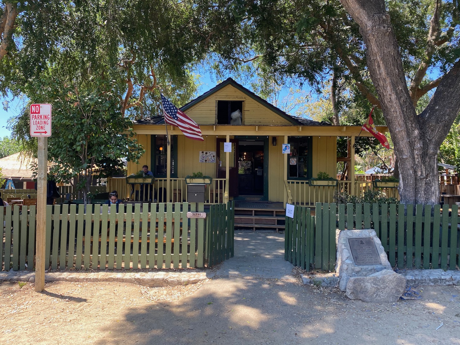 a yellow house with a fence and a flag