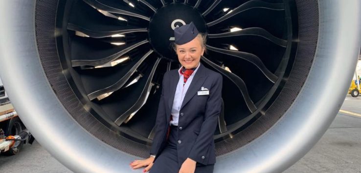 a woman in uniform standing in front of a large jet engine