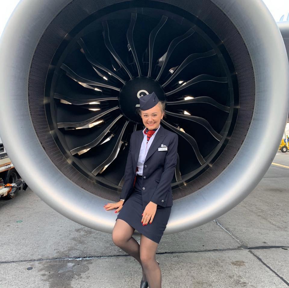 a woman in uniform standing in front of a large jet engine