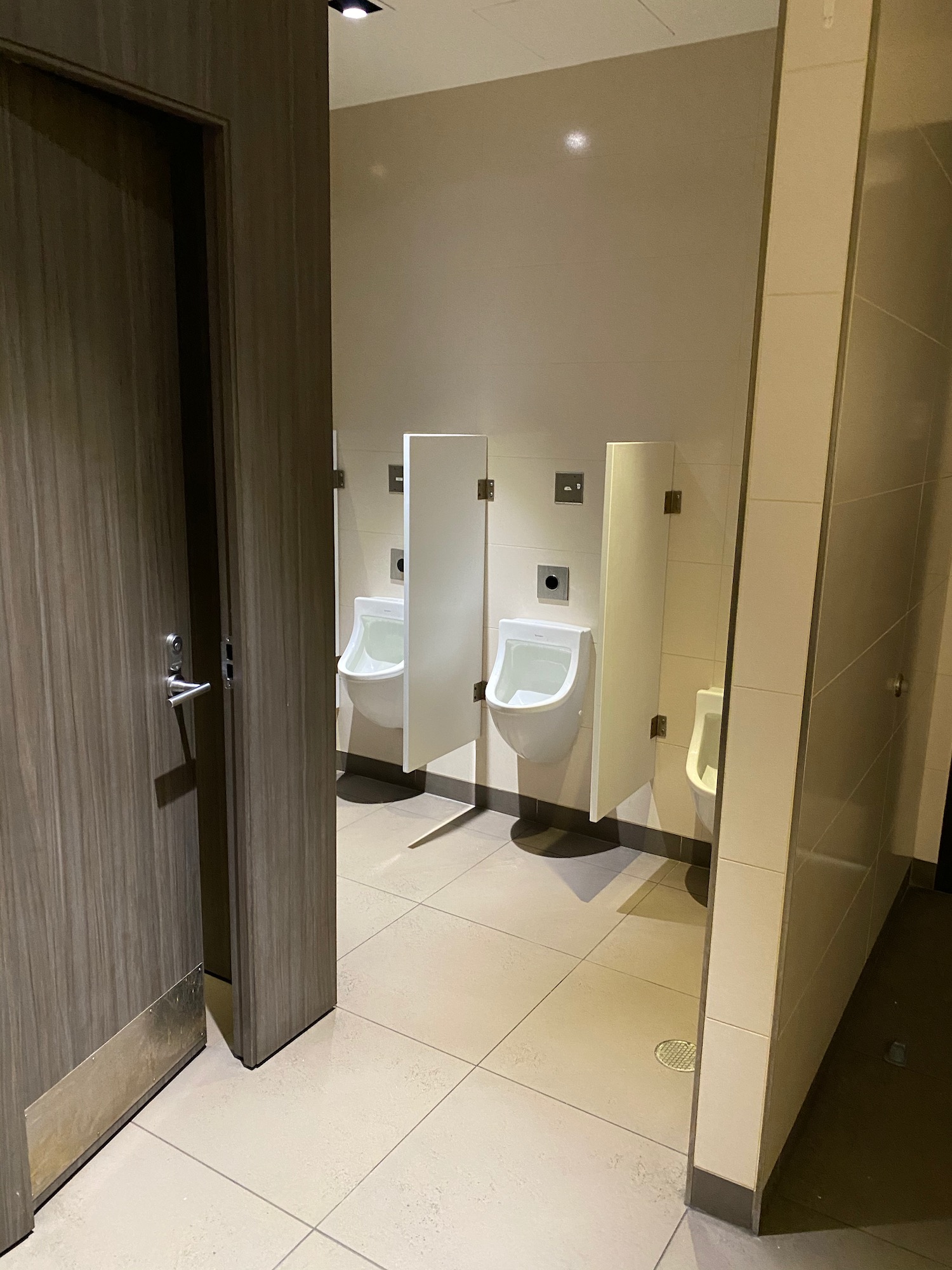 a bathroom with urinals and a door