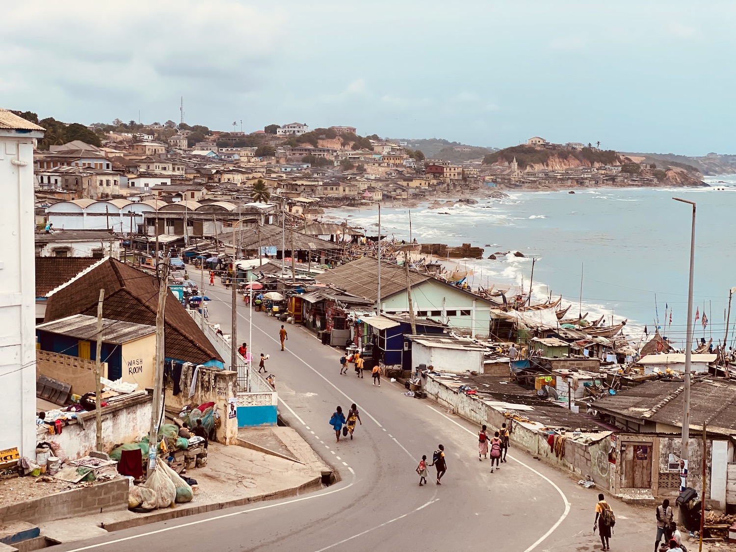 a street with people walking on it and a body of water in the background