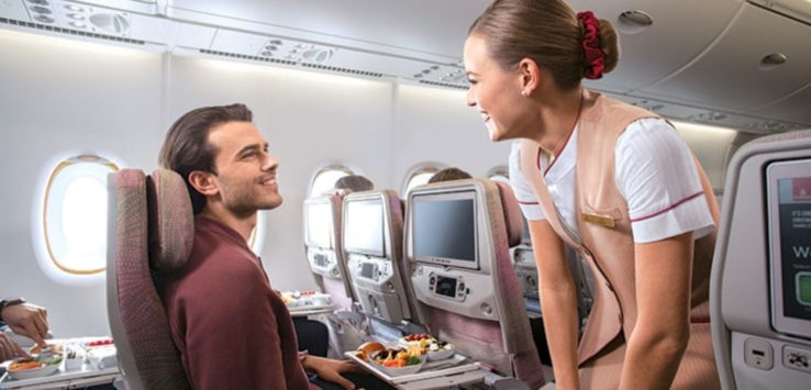 a woman smiling at a man sitting in an airplane