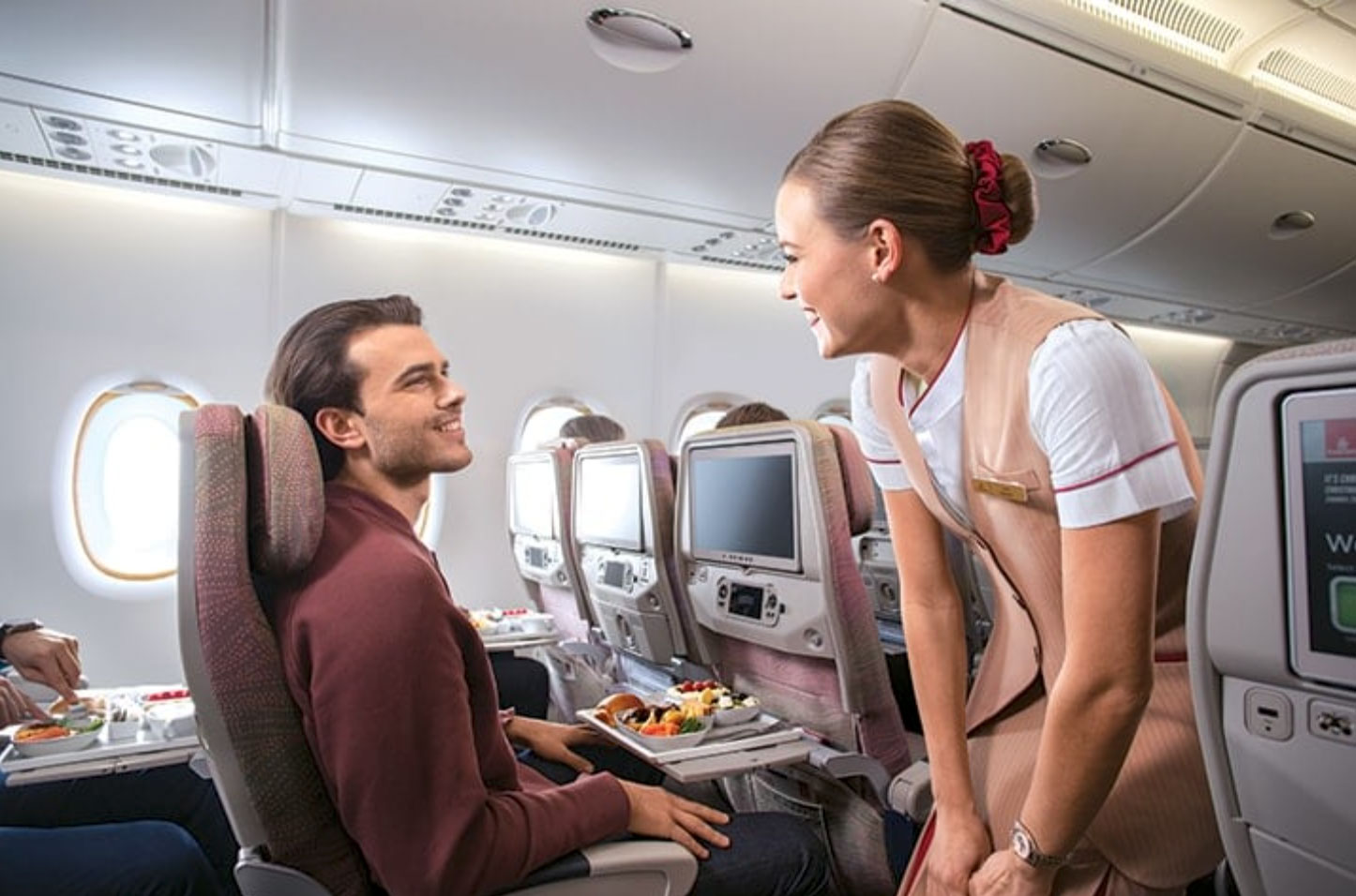 a woman smiling at a man sitting in an airplane