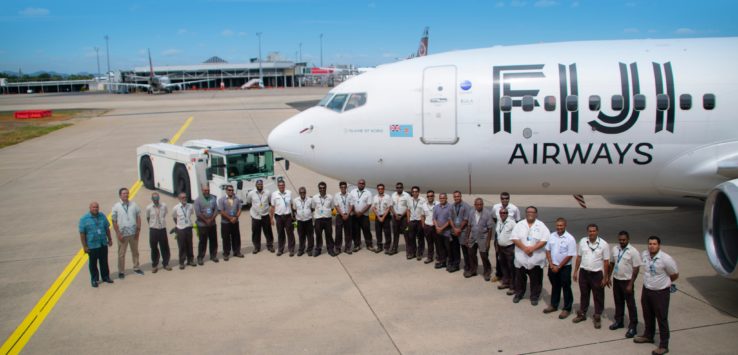 a group of people standing in front of a plane