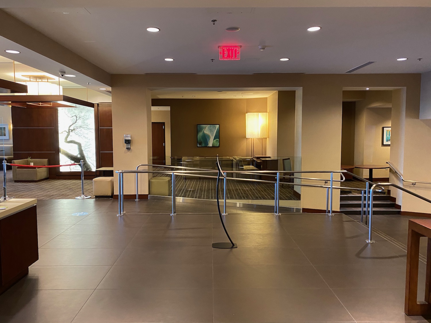 a large hall with a railing and a red exit