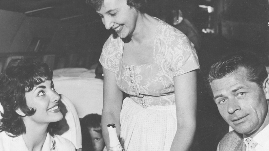 a woman smiling at a bottle of champagne