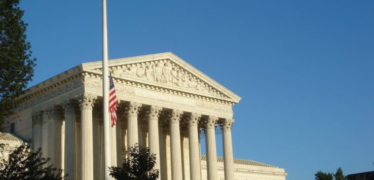 a white building with columns and a flag pole