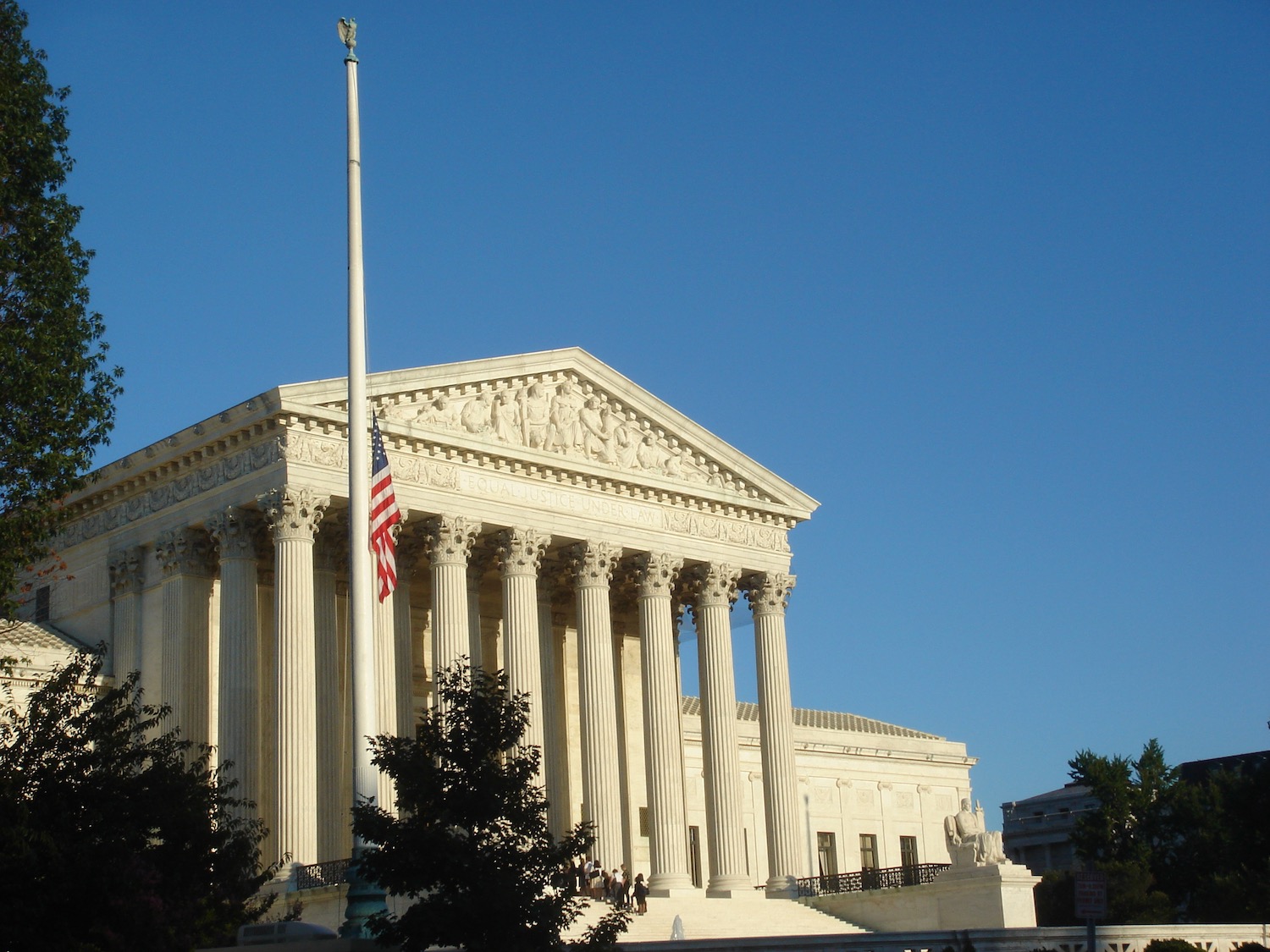 a white building with columns and a flag pole