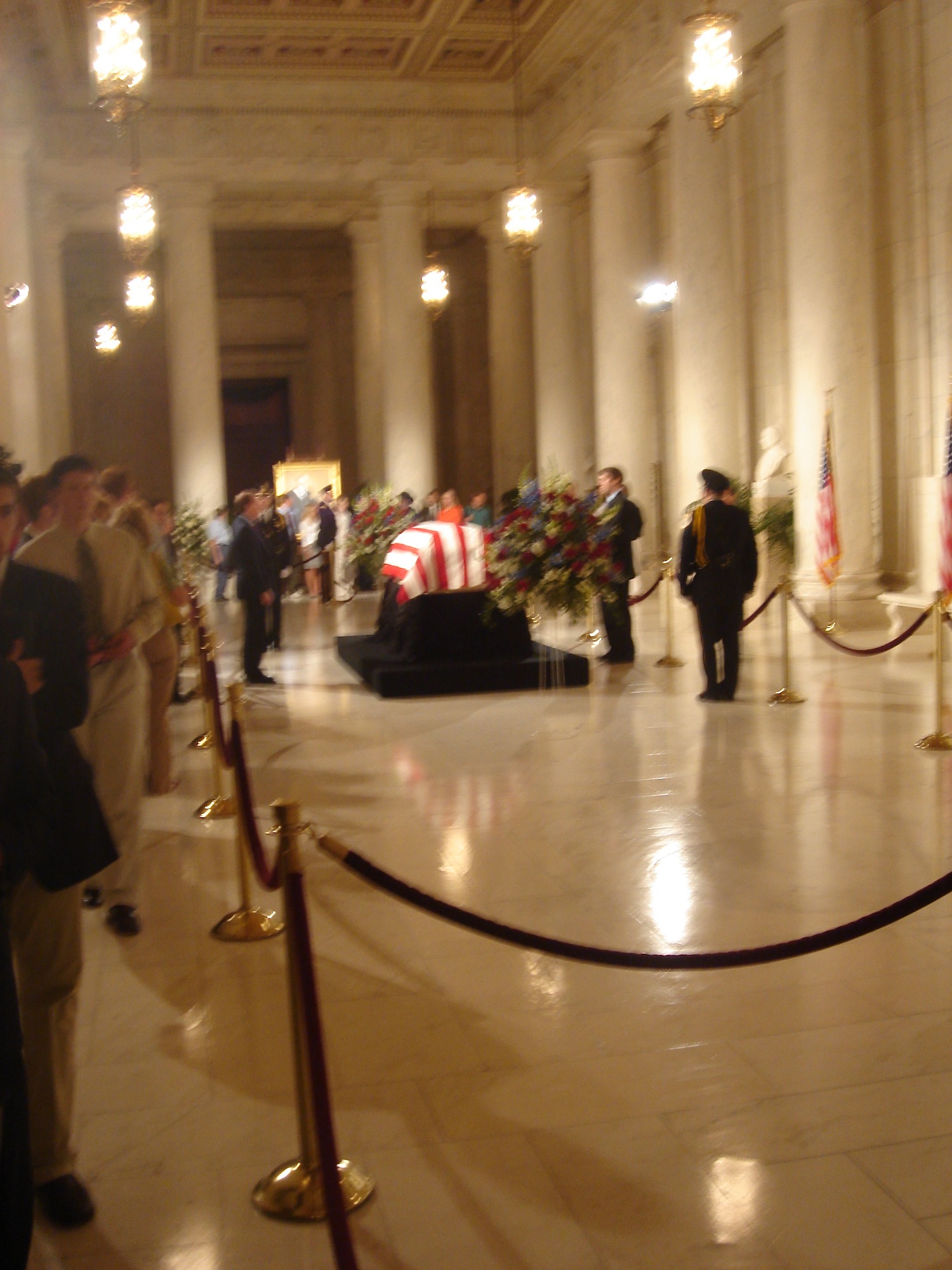 a group of people in a room with a casket in front of them