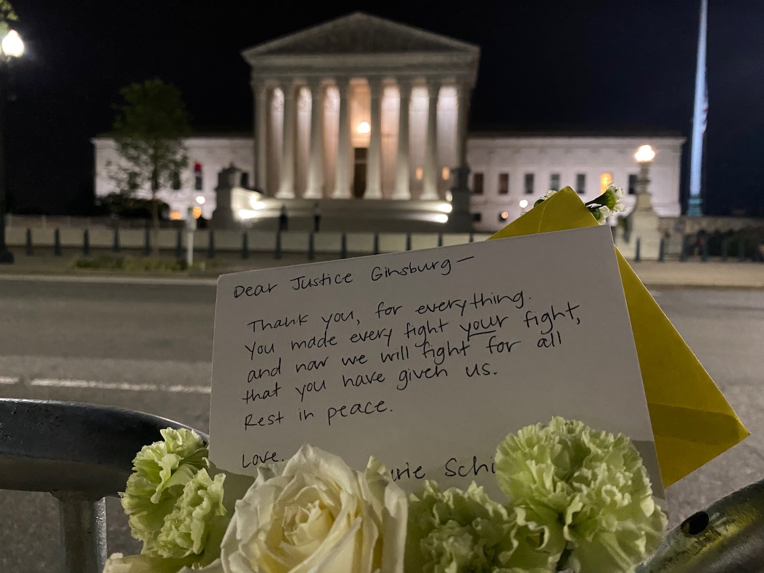 a note on a postcard with flowers in front of a building