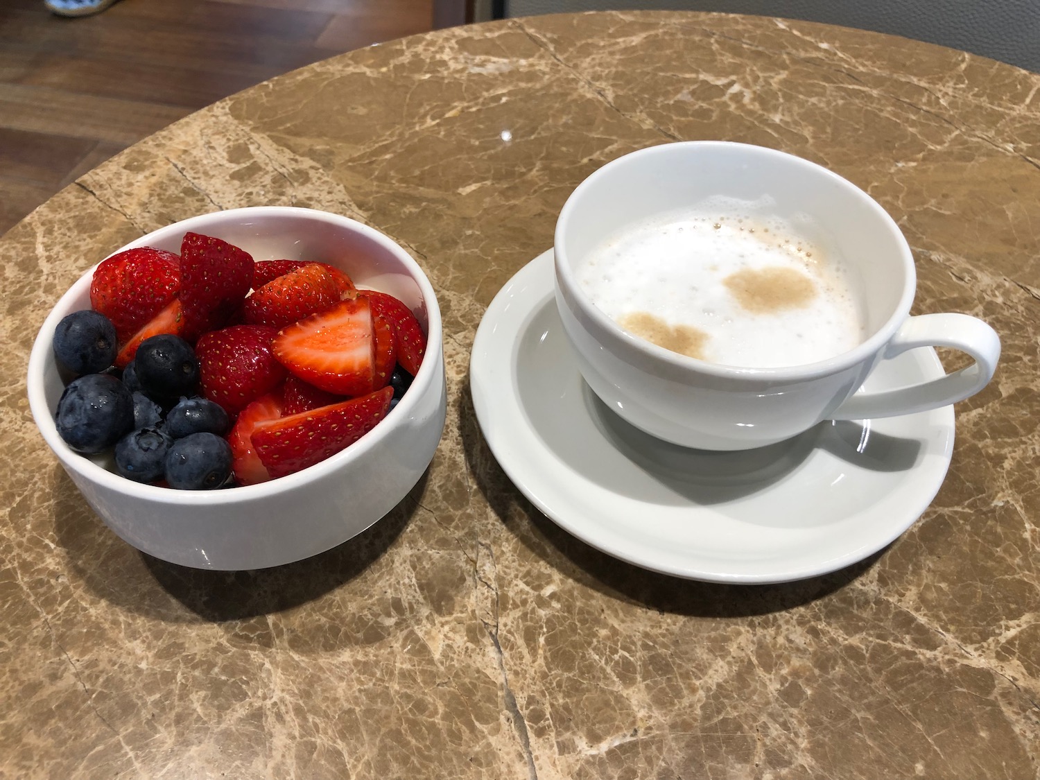 a bowl of strawberries and blueberries next to a cup of coffee