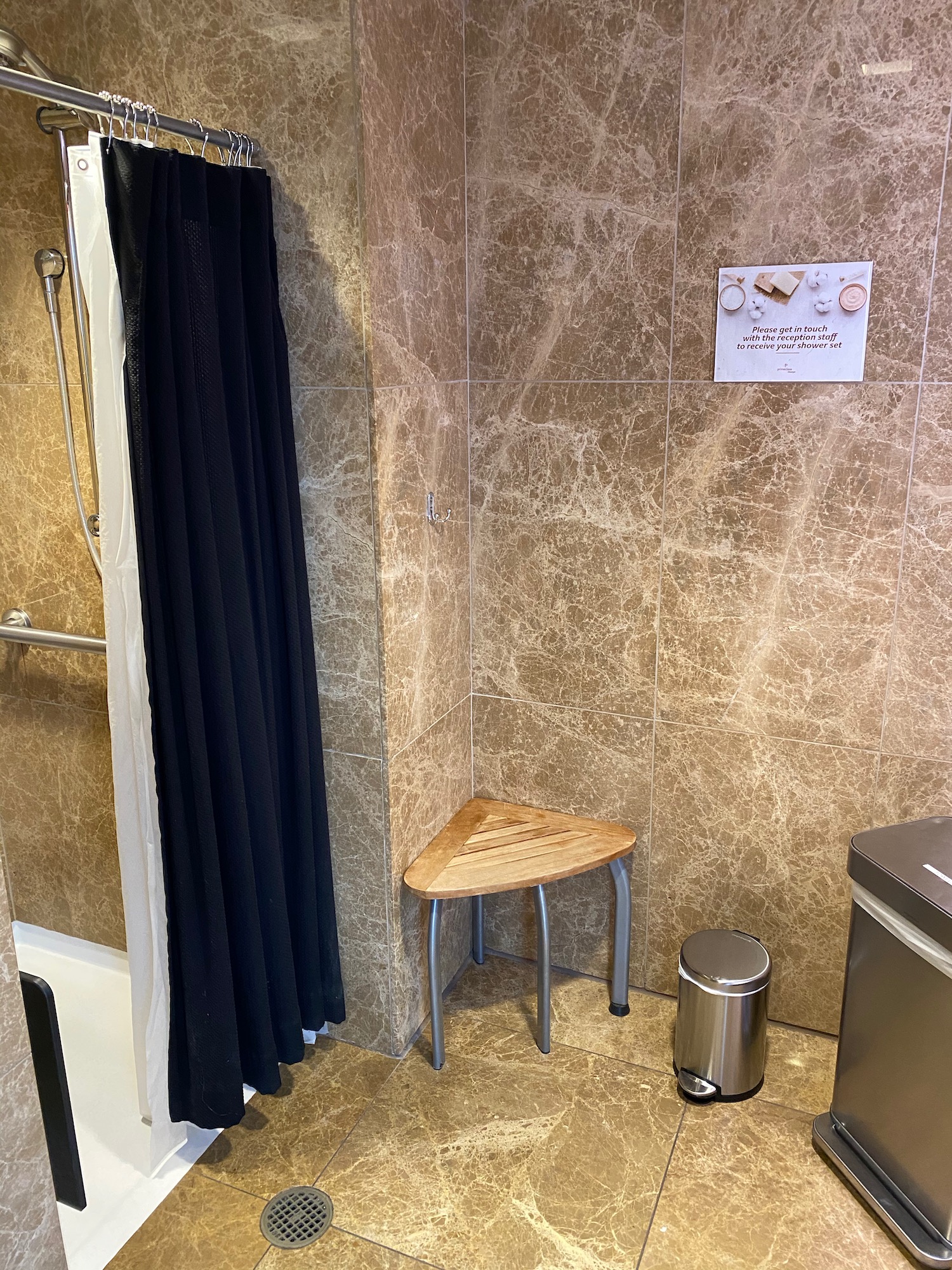 a shower with a stool and a black curtain