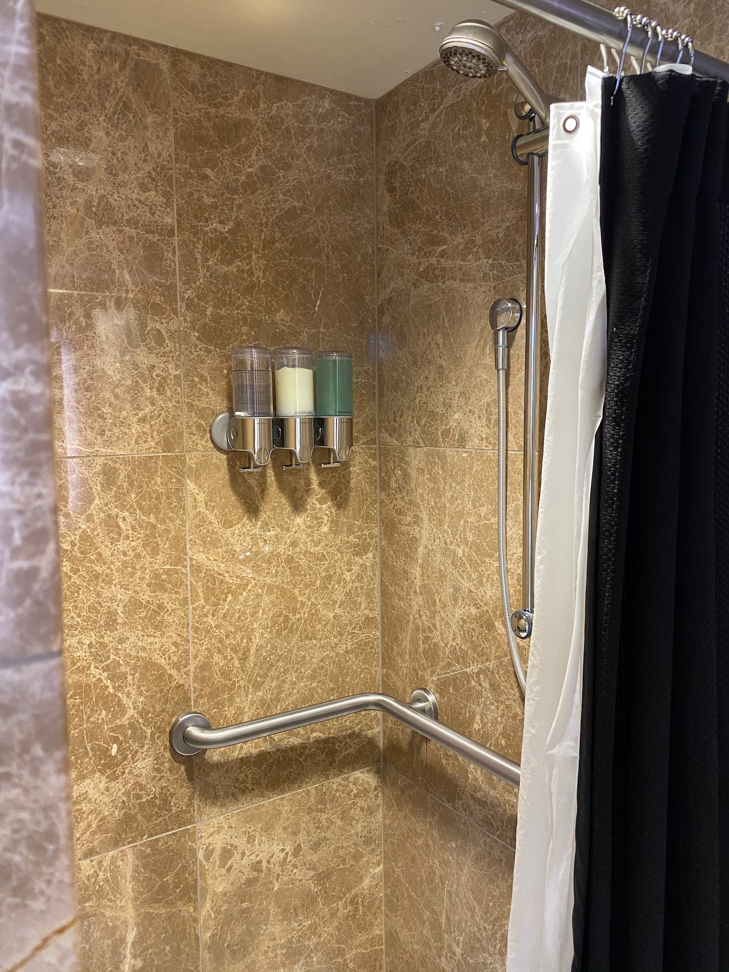 a shower with soap dispensers and shower curtain