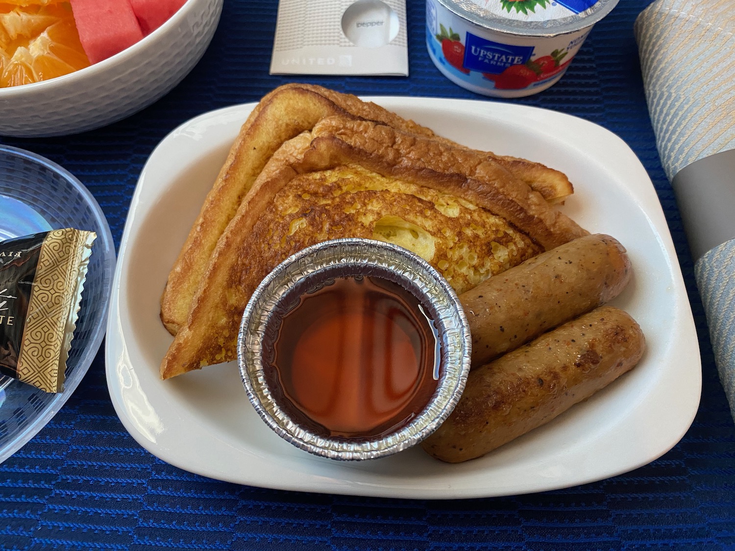 a plate of french toast sausages and syrup