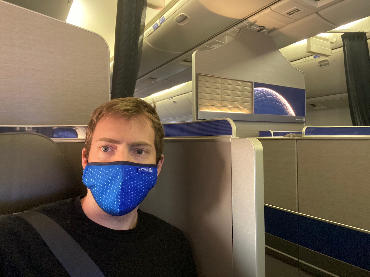 a man wearing a blue mask on an airplane