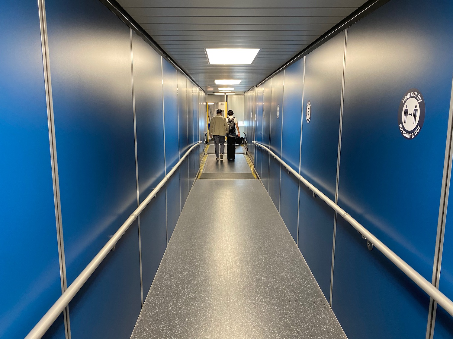 a hallway with blue walls and a couple of people walking