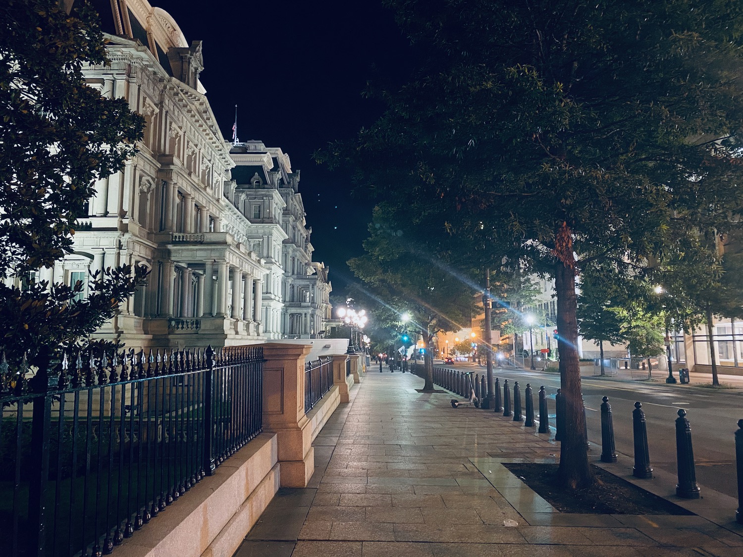 a sidewalk with trees and buildings at night