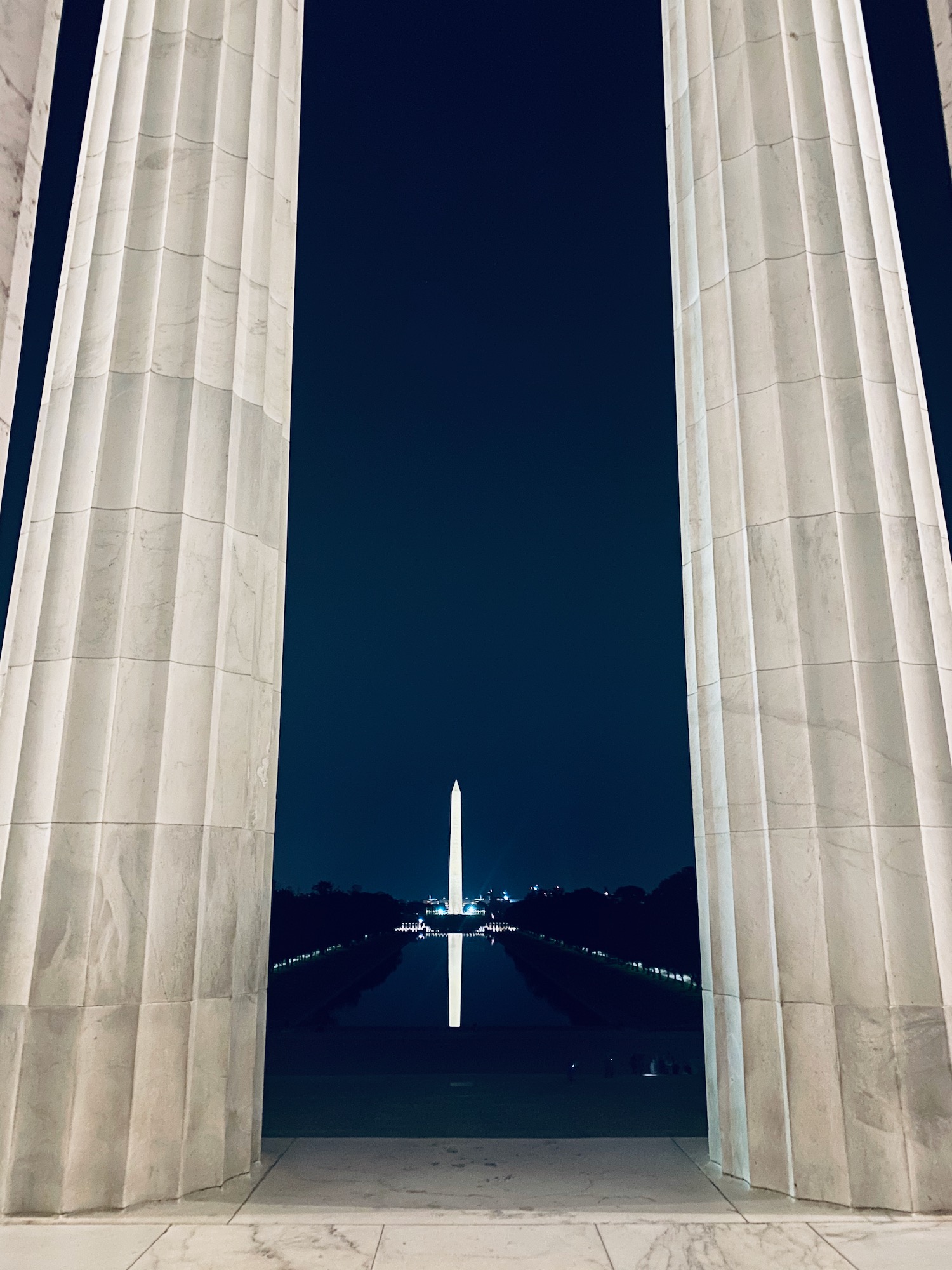 a tall white pillars with a tower in the background