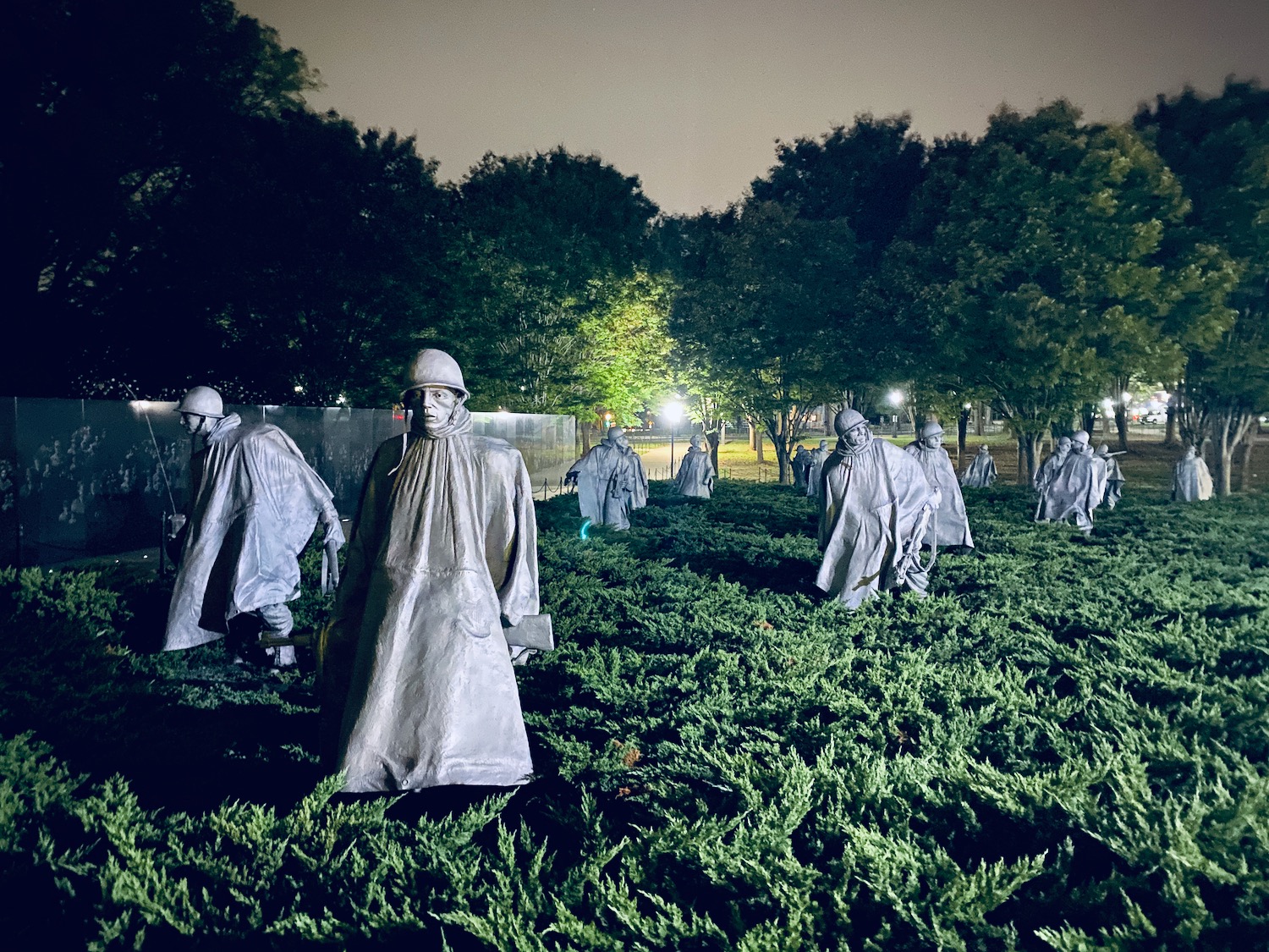 statues of people in white cloths in a field with Korean War Veterans Memorial in the background