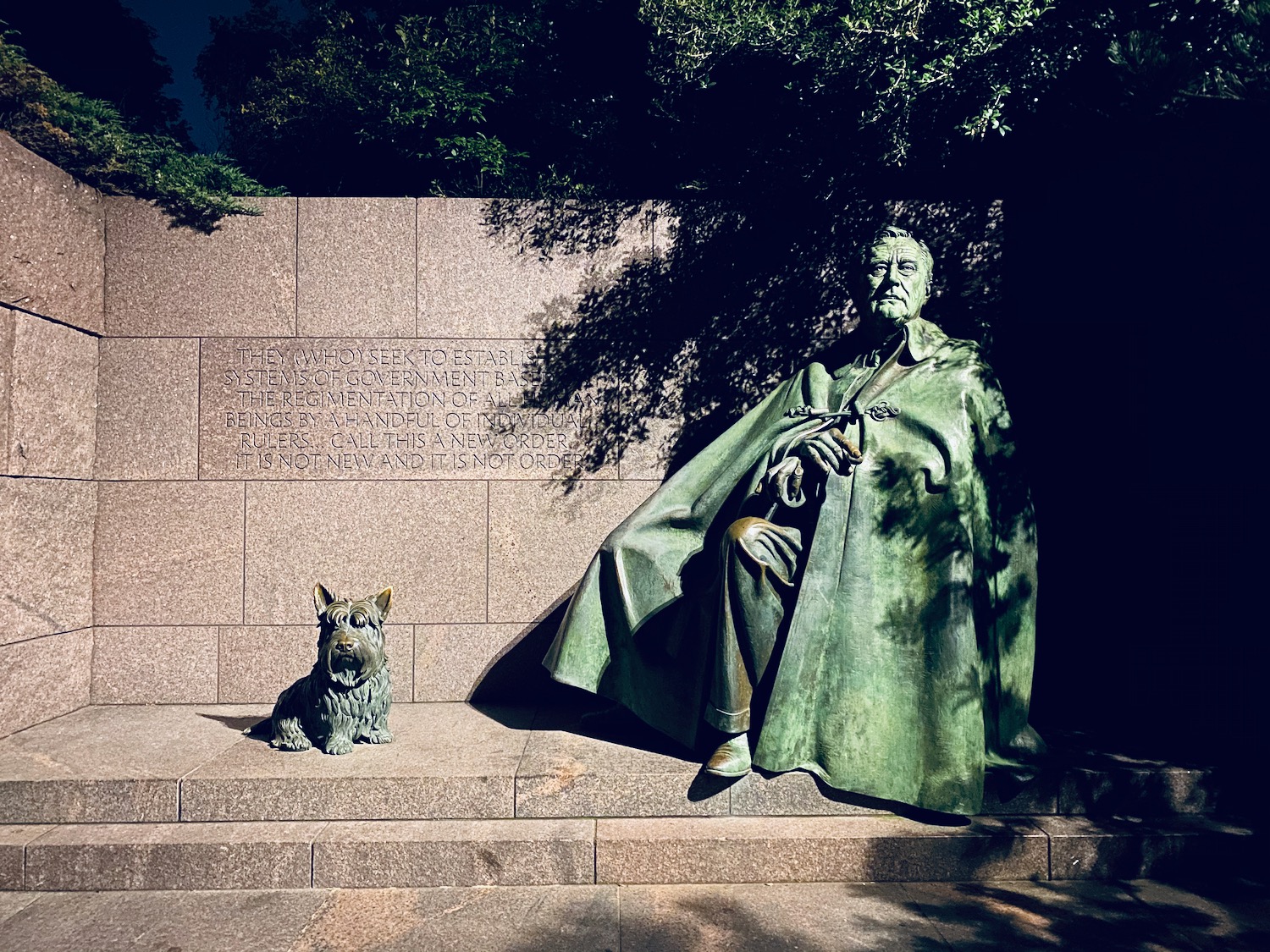 a statue of a man and a dog with Franklin Delano Roosevelt Memorial in the background