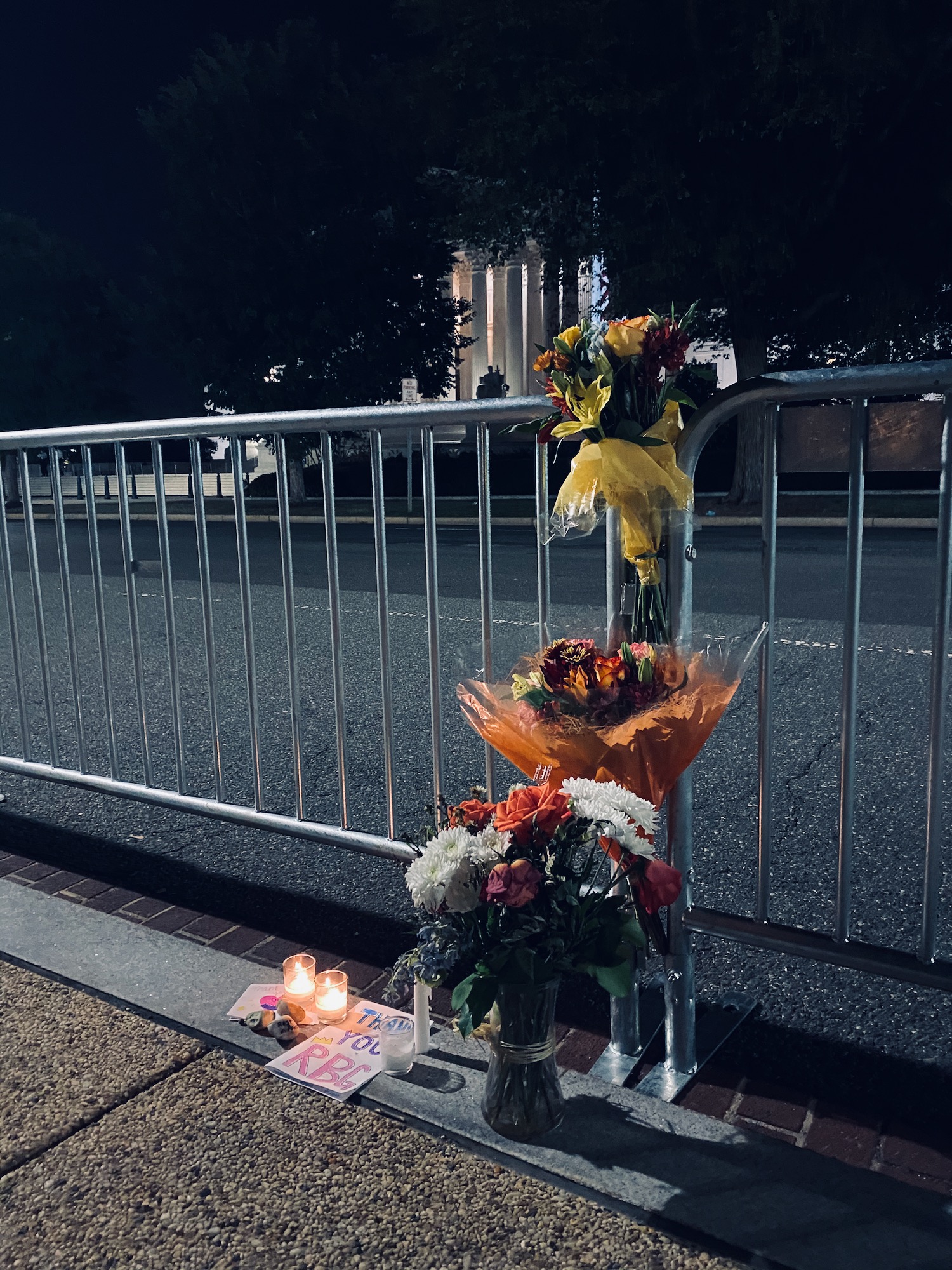 flowers and candles next to a fence