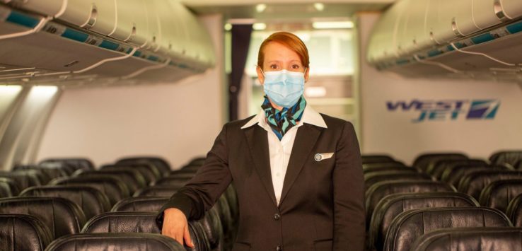 a woman wearing a mask standing in a plane