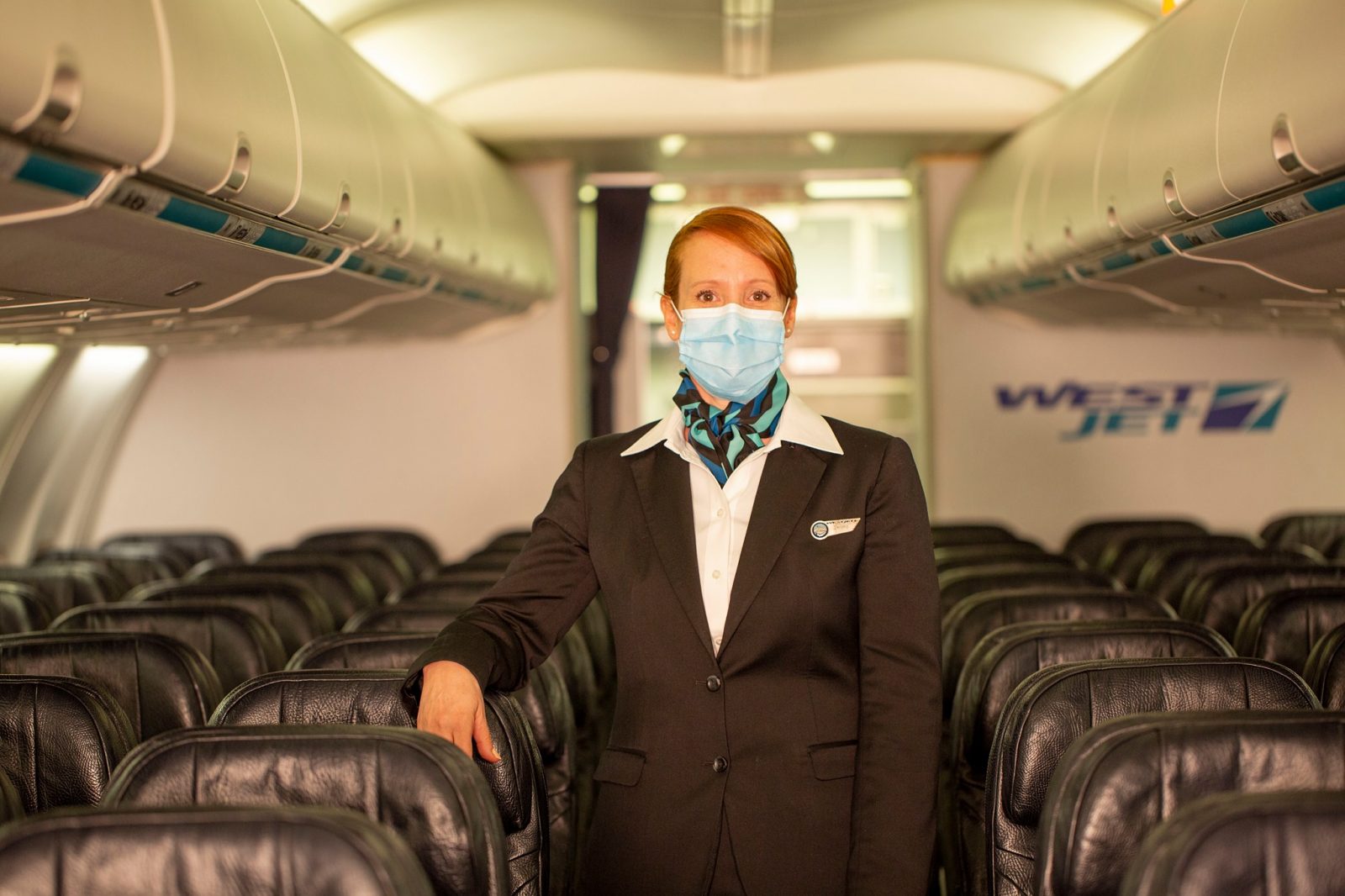 a woman wearing a mask standing in a plane