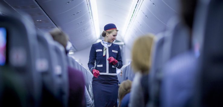 a woman in a blue suit walking on an airplane