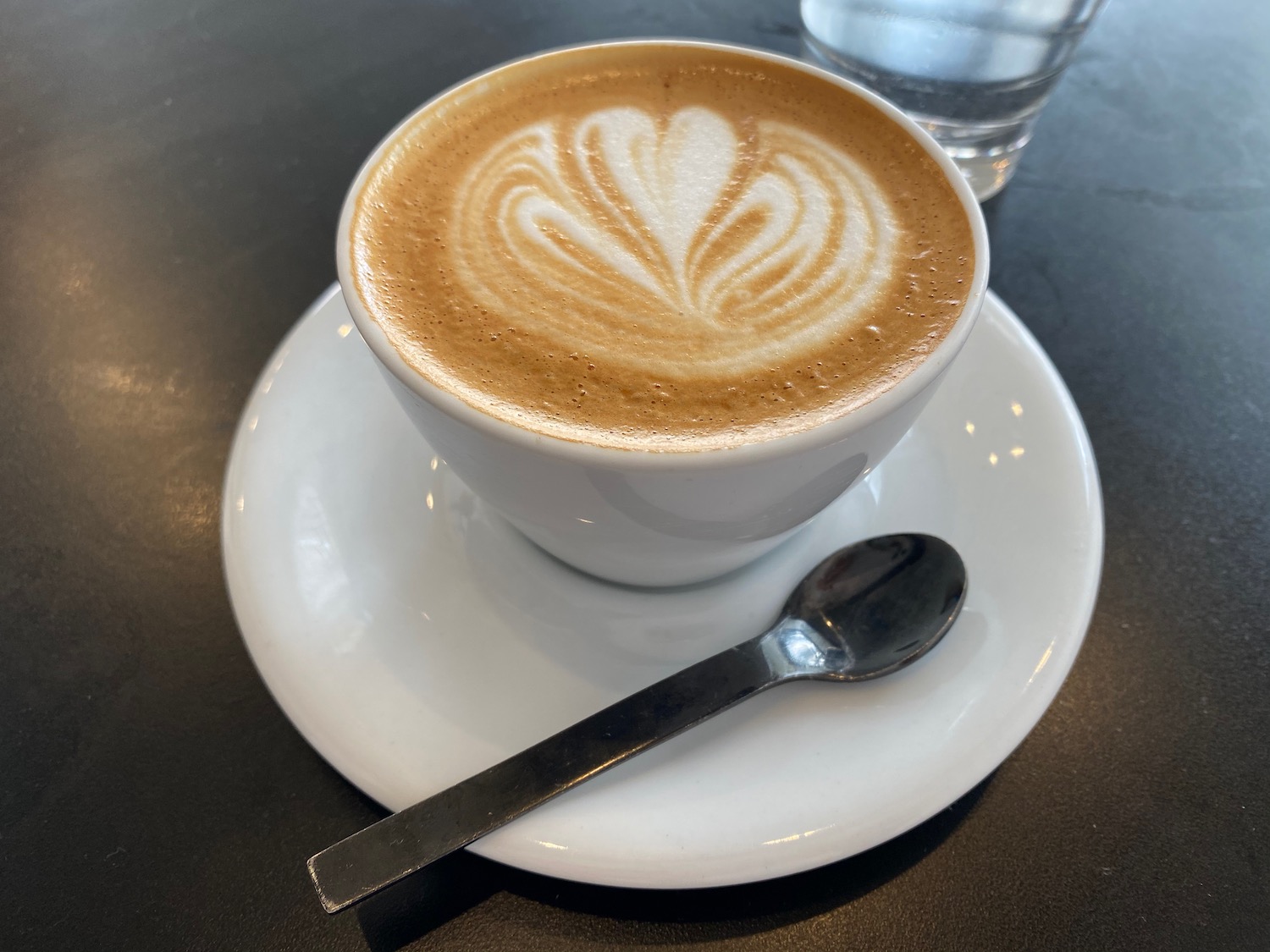 a cup of coffee with a spoon and a glass of water