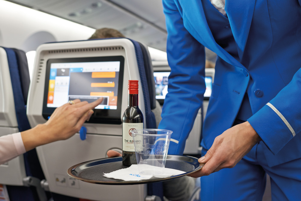 a person holding a tray with a bottle and a glass