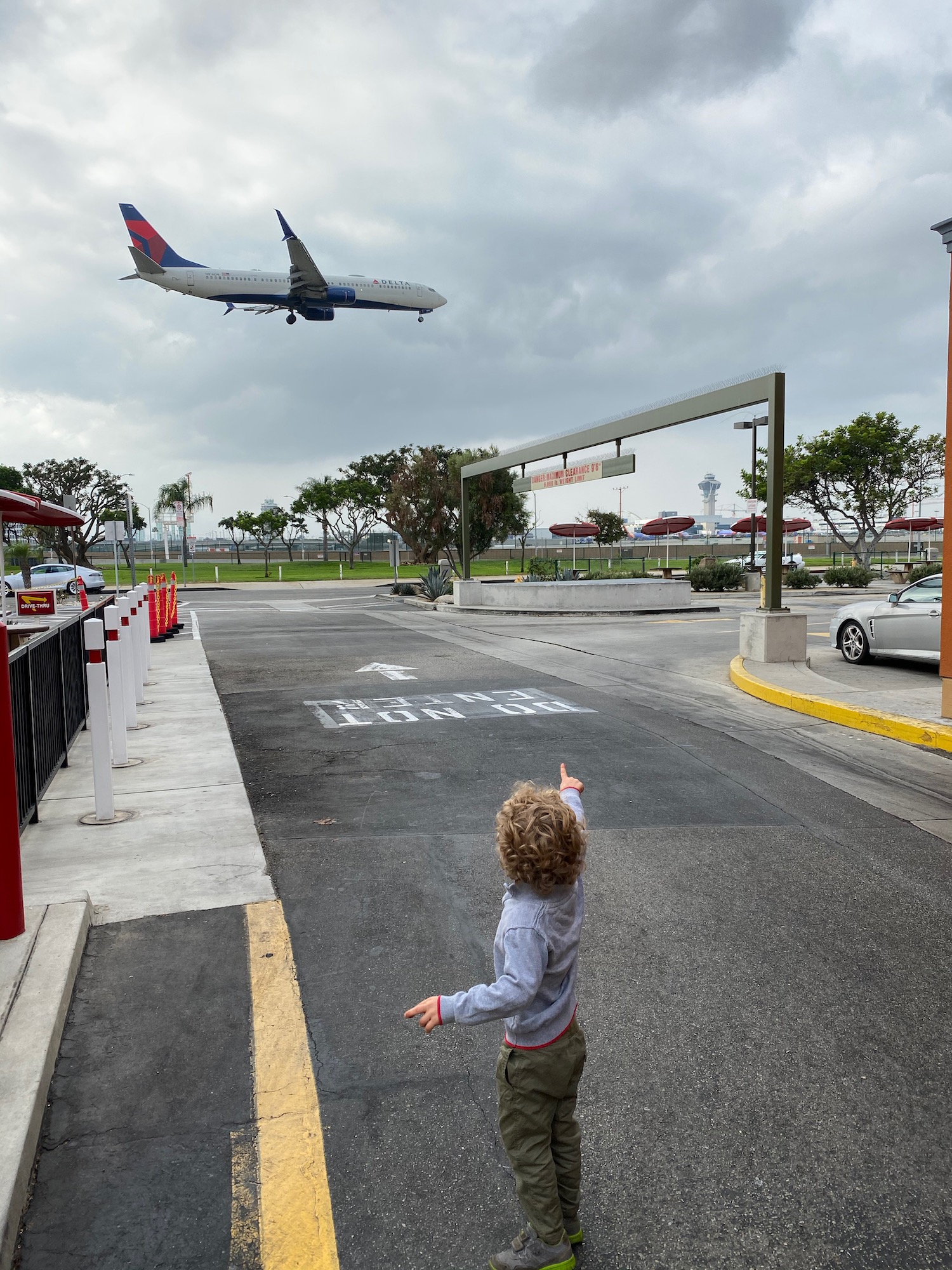 a boy pointing at an airplane in the sky