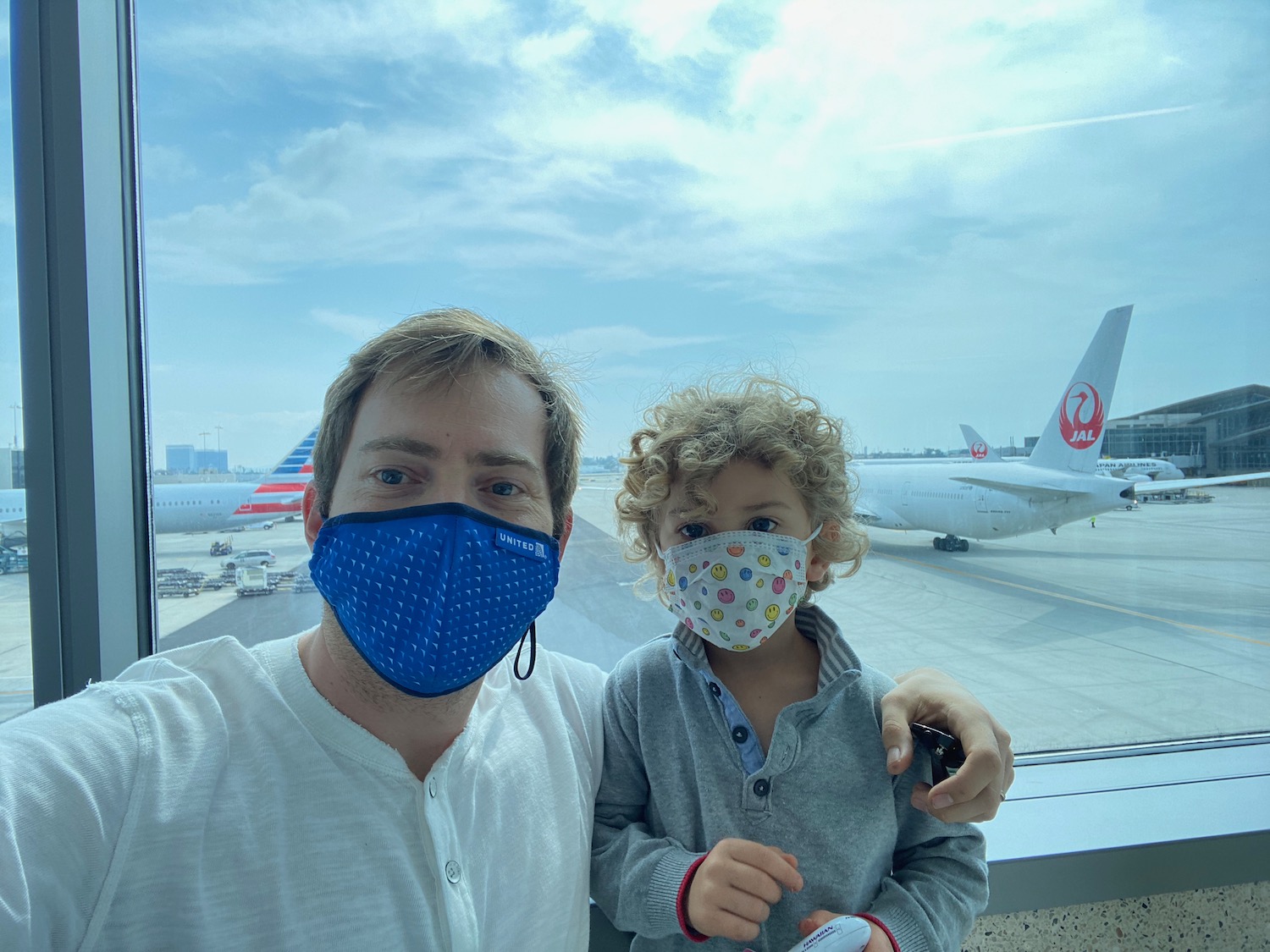 a man and child wearing face masks taking a selfie