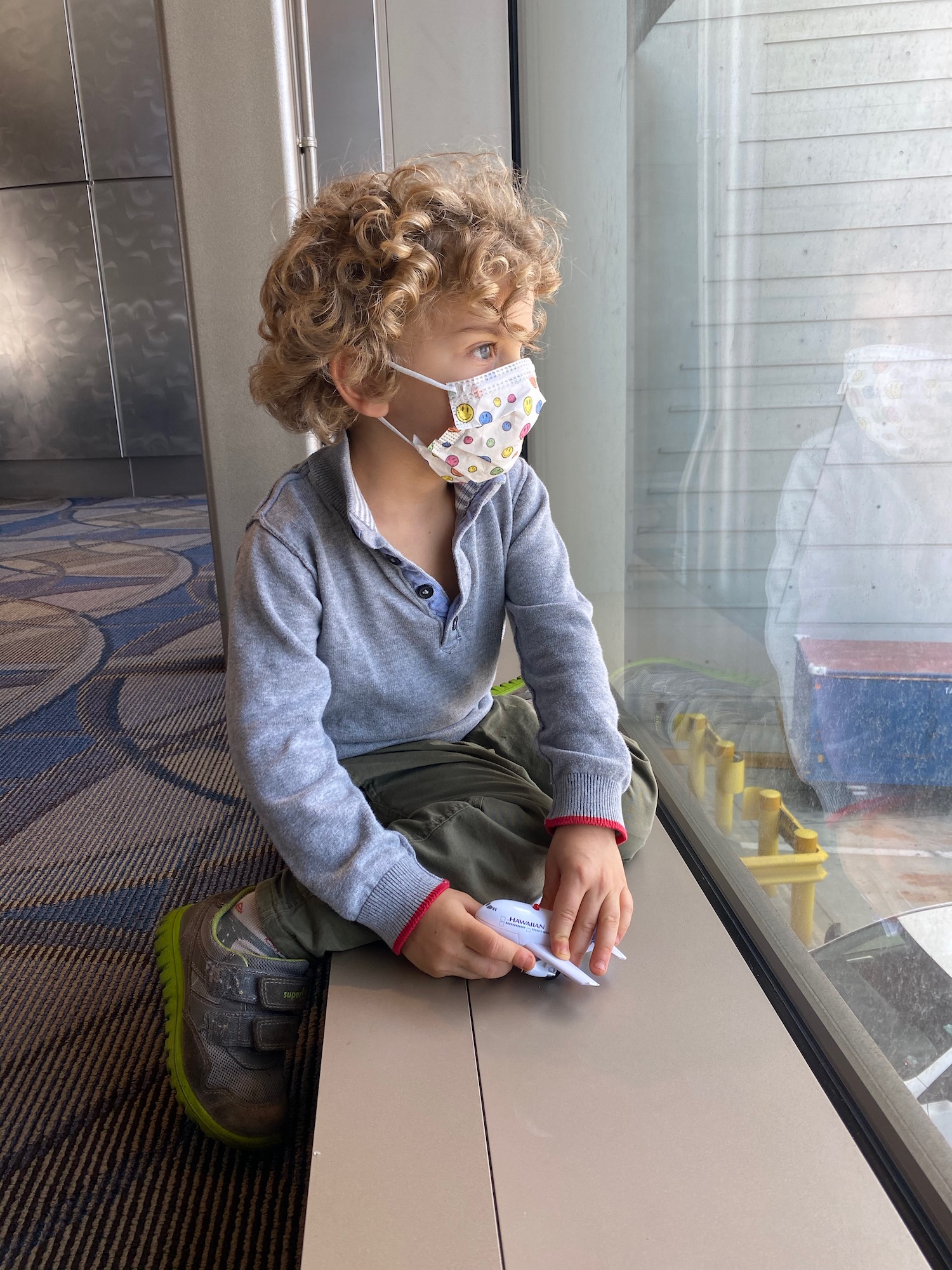 a child wearing a mask sitting on a window sill