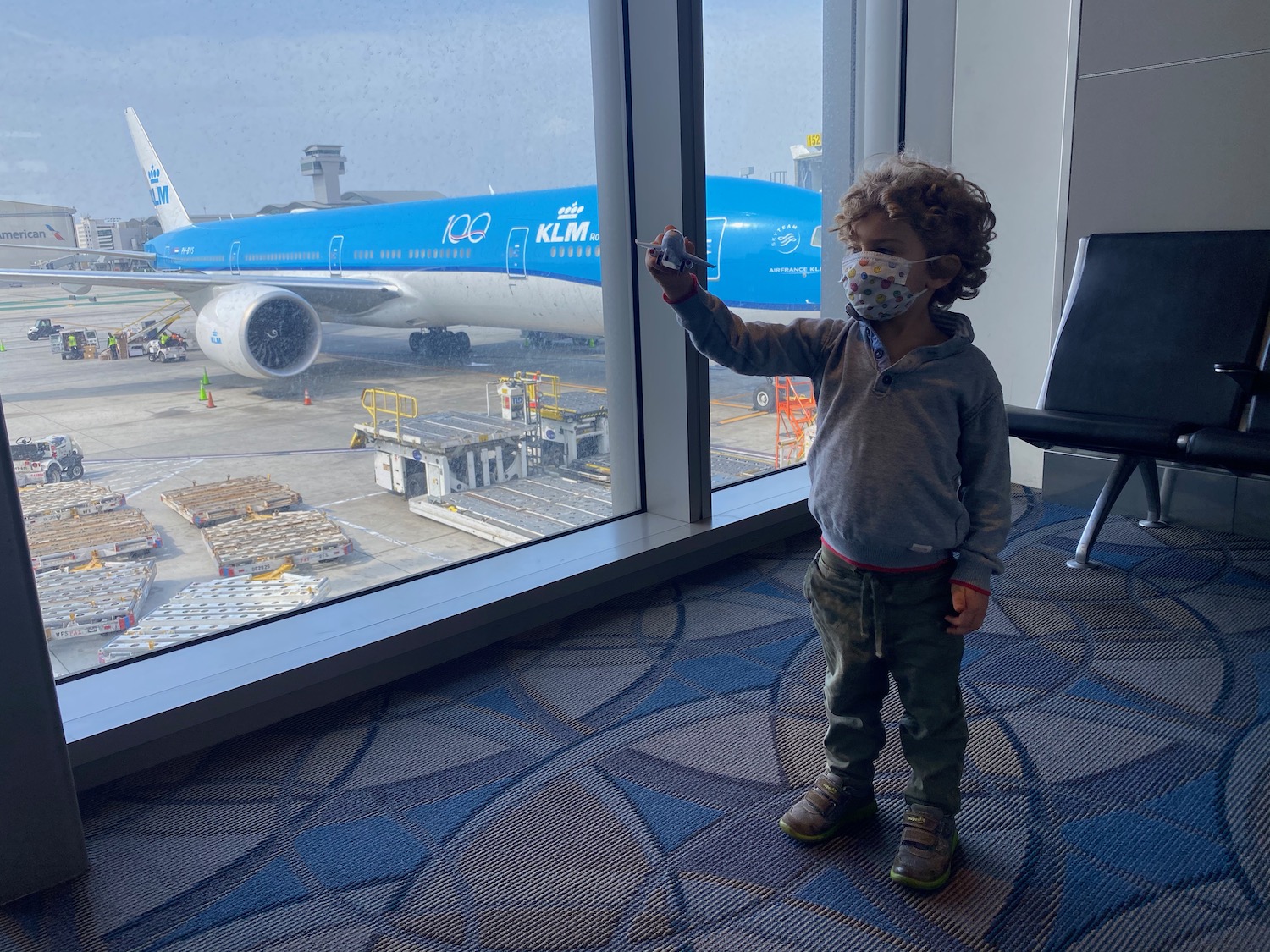 a child standing in front of a window with a mask