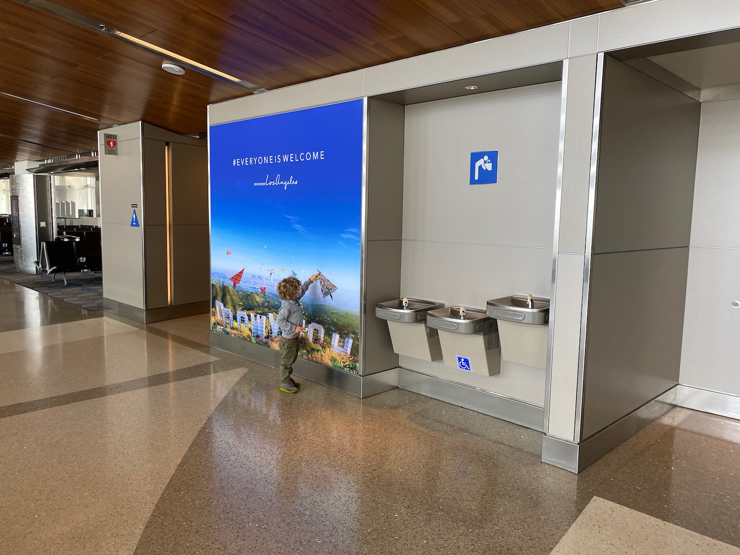 a child standing in a room with a sign and water fountains