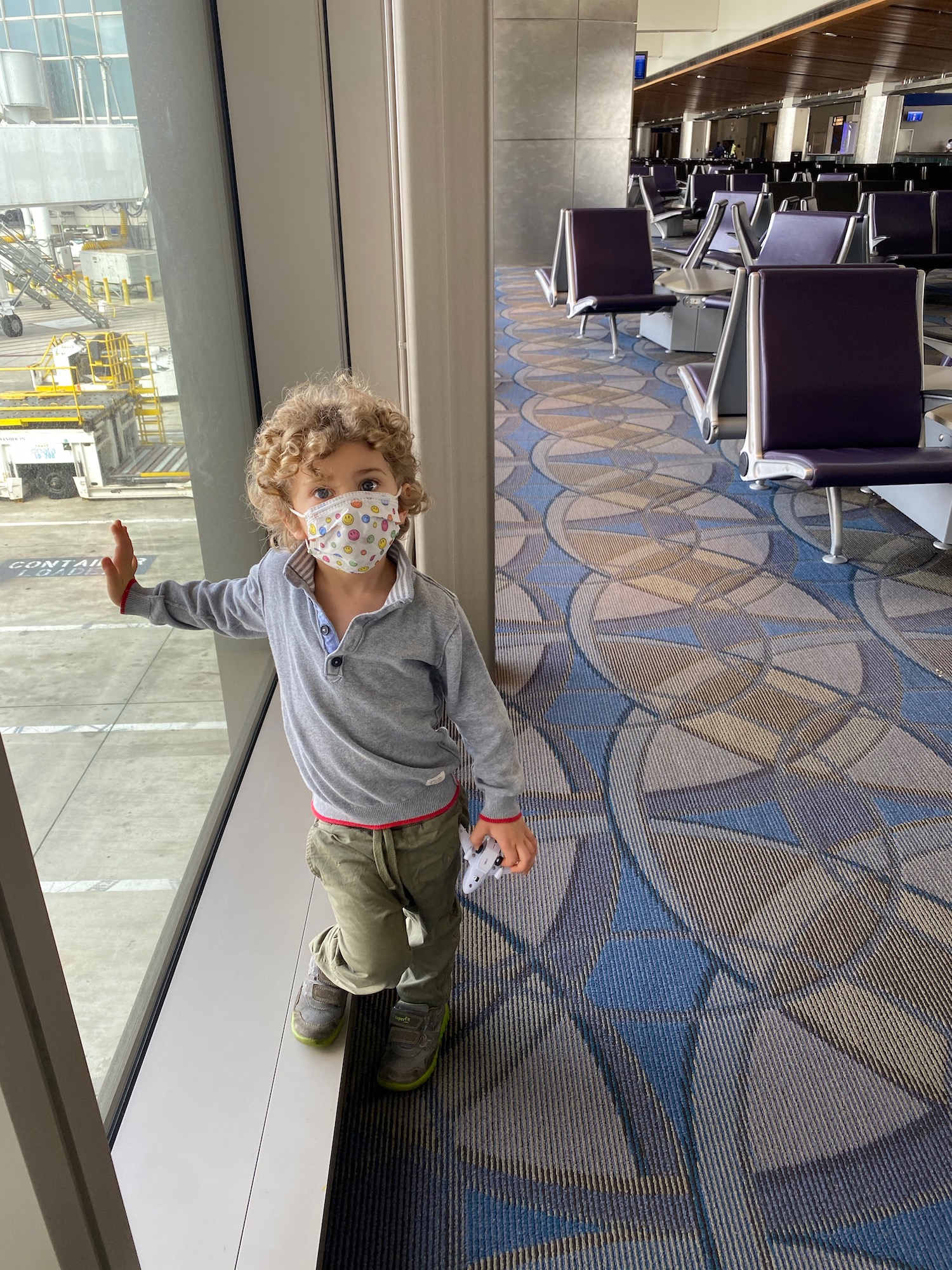 a child wearing a face mask standing in an airport