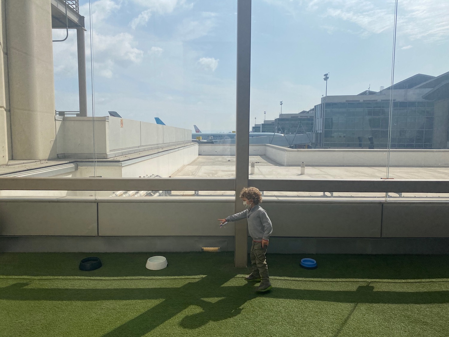 a child standing on a green surface with a large window