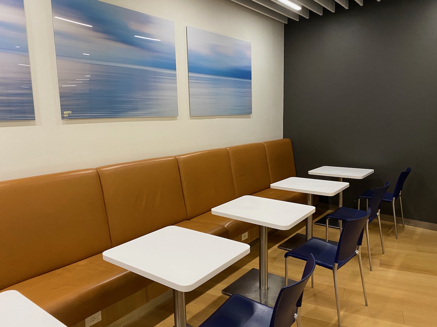 a booth with white tables and blue chairs