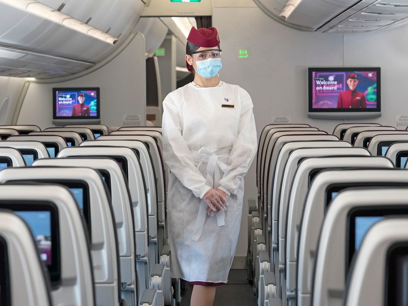 a woman wearing a face mask and a white coat in an airplane