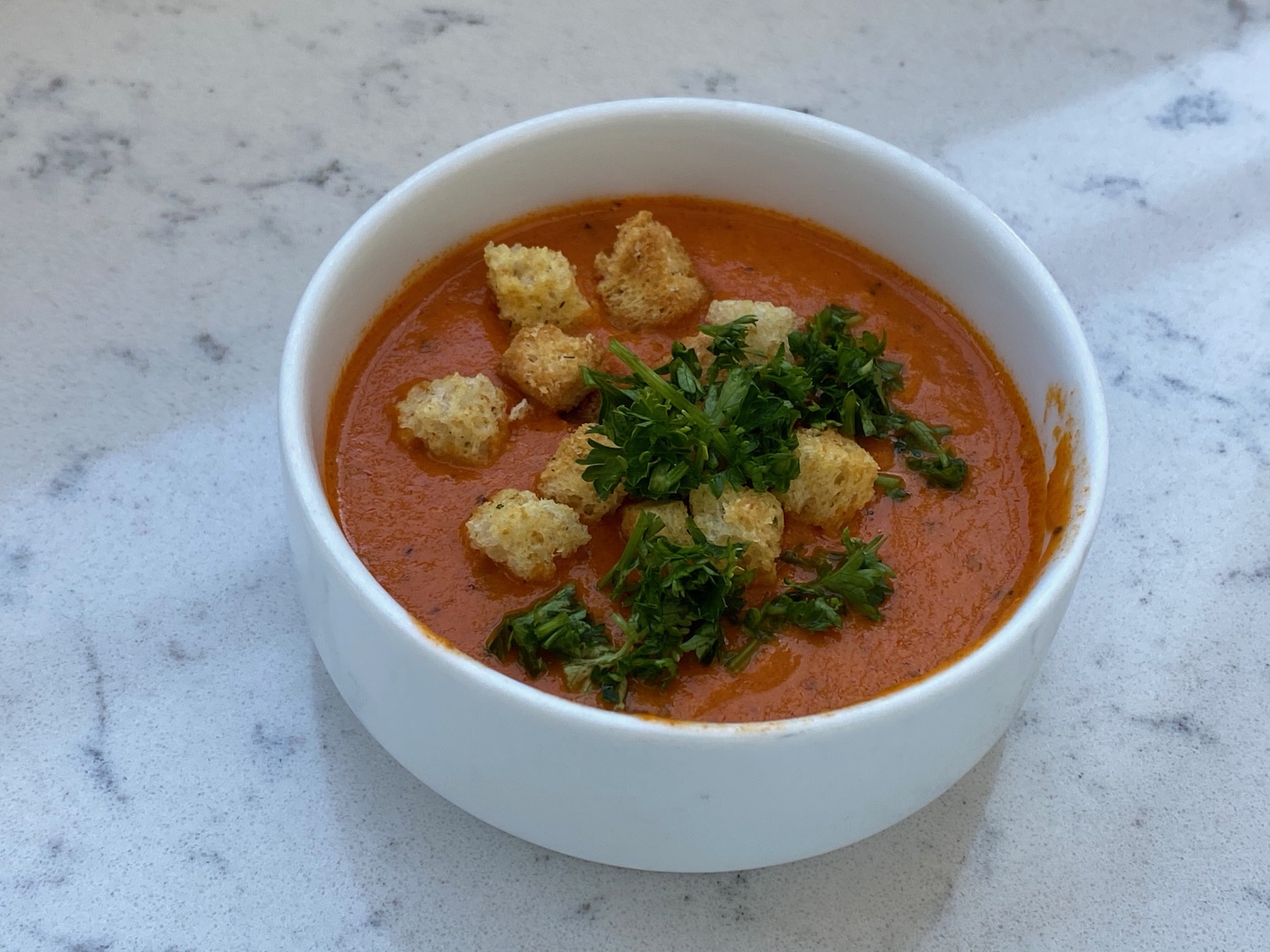 a bowl of soup with croutons and parsley