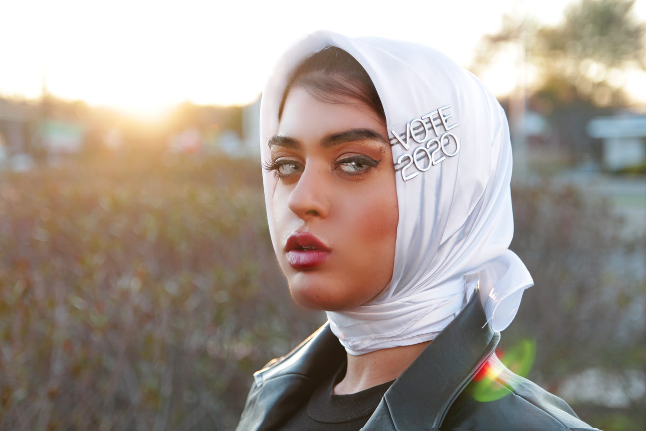 a woman wearing a white scarf with a silver brooch on her head