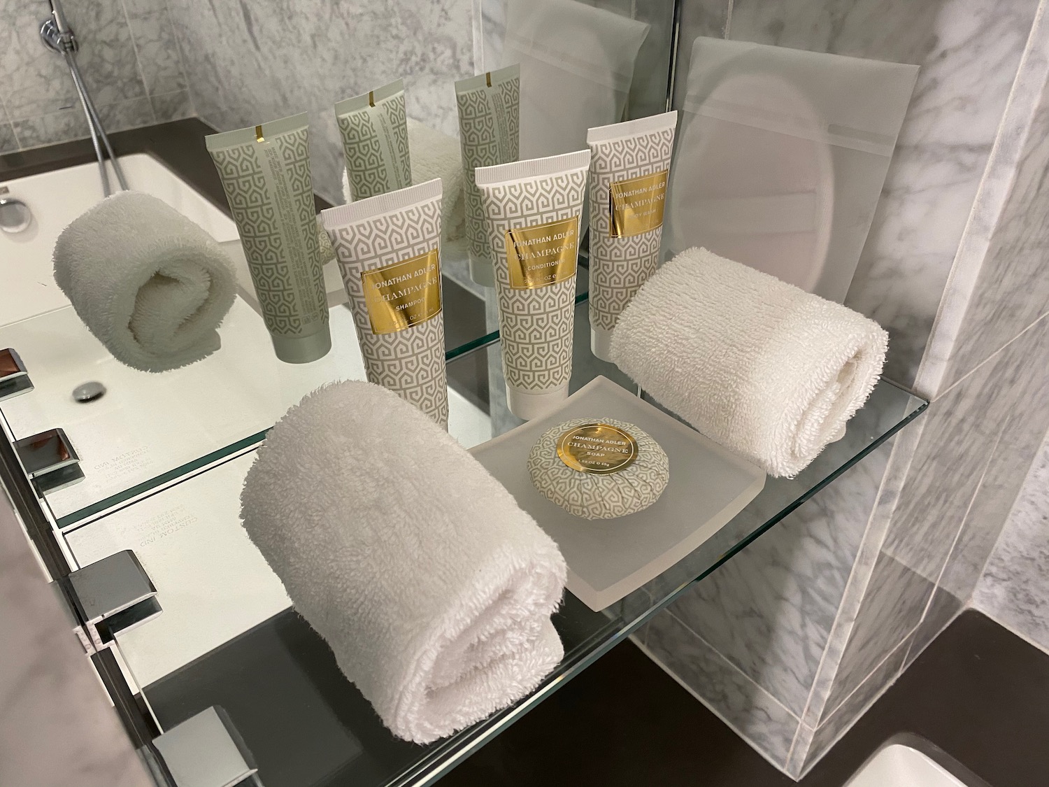 a group of towels and a soap on a glass shelf