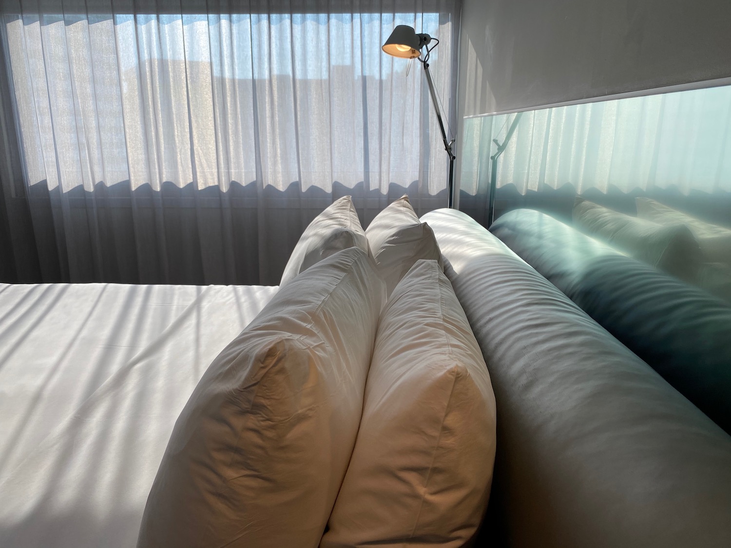 a bed with pillows and a lamp in the background