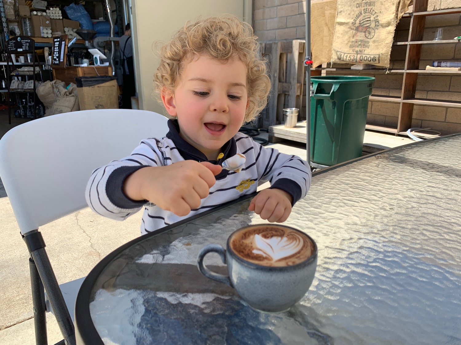 a child sitting at a table with a cup of coffee