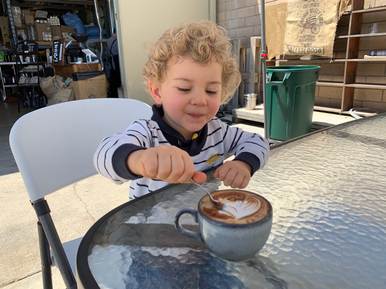a child with curly hair and a cup of coffee