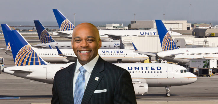 a man in a suit and tie standing in front of airplanes
