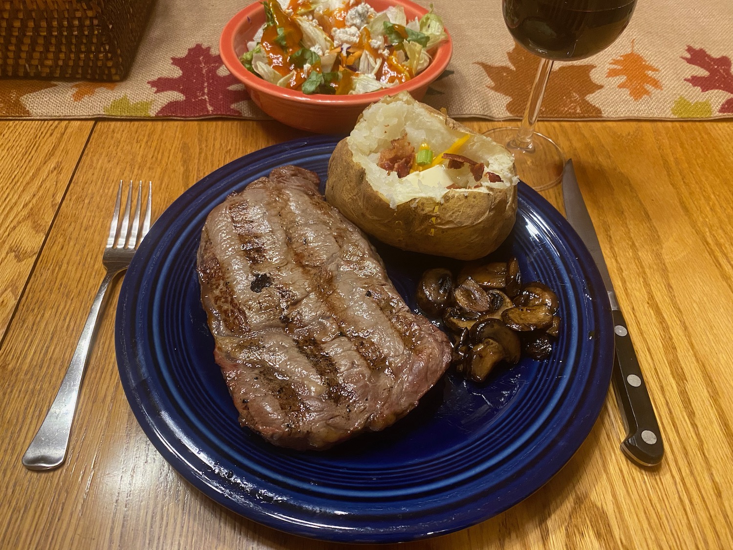 a plate of steak and baked potato with a side of salad