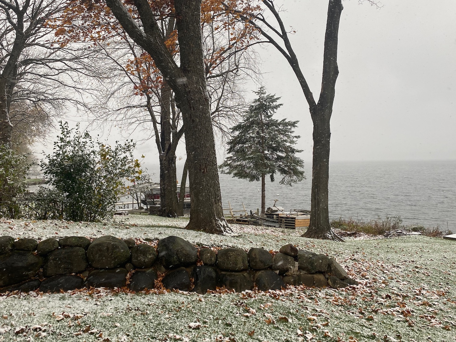 a snow covered ground with rocks and trees by the water