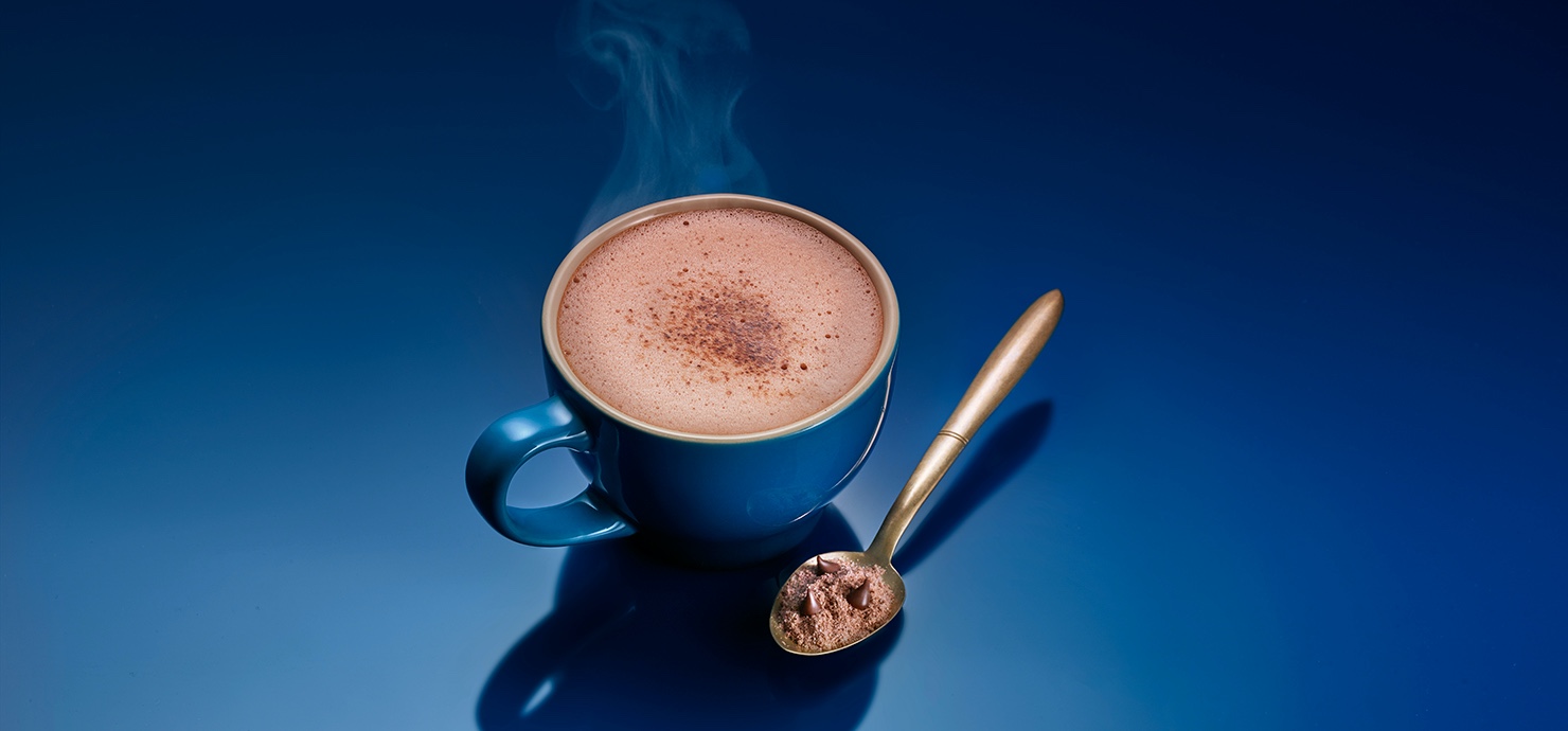 a cup of hot chocolate with a spoon and a blue background